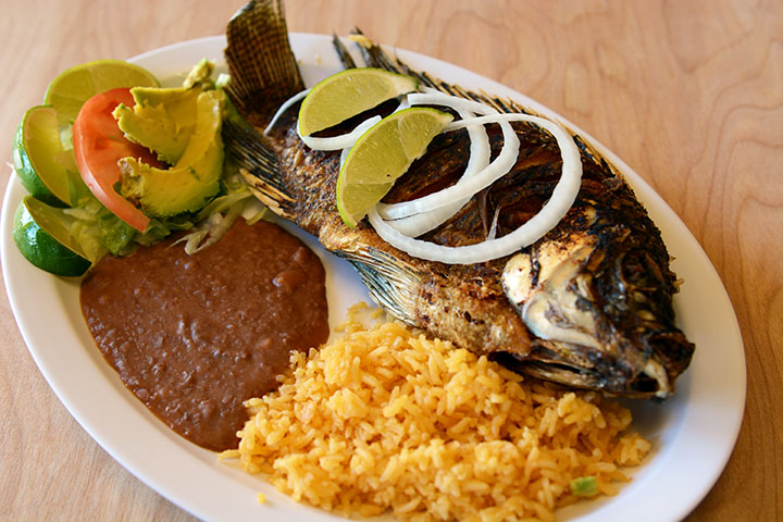 Fried whole fish is a traditipnal Mexican and Salvadoran dish that tastes incredible, and it looks as if eating in a beach besides a fire